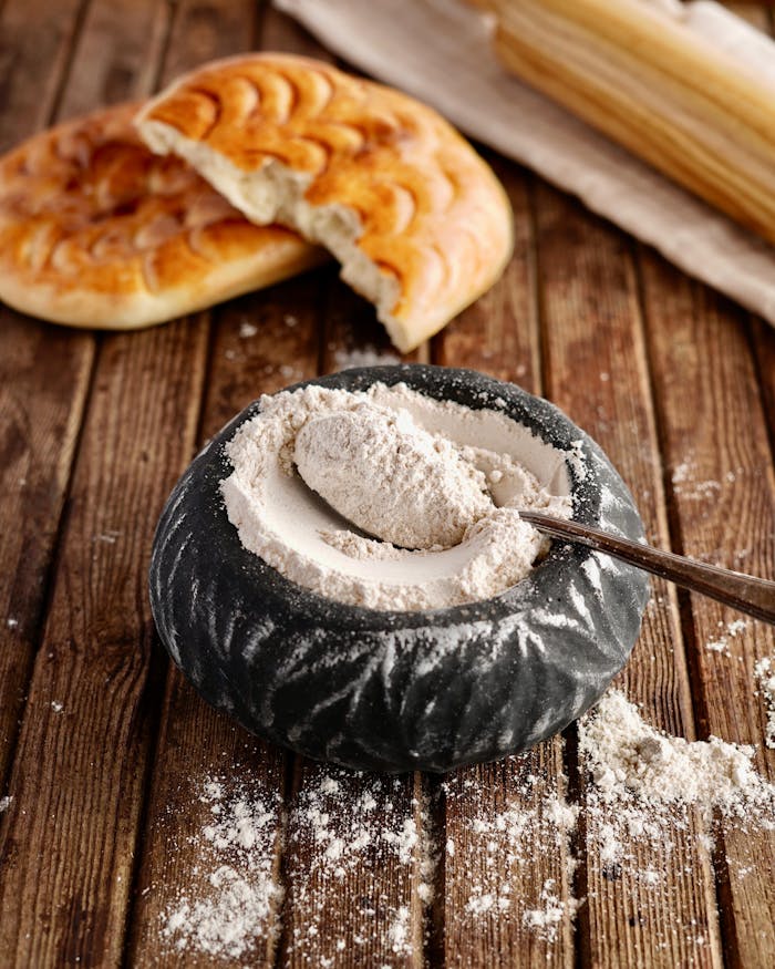 Freshly baked bread with flour in a bowl on a rustic wooden table. Perfect for culinary themes.