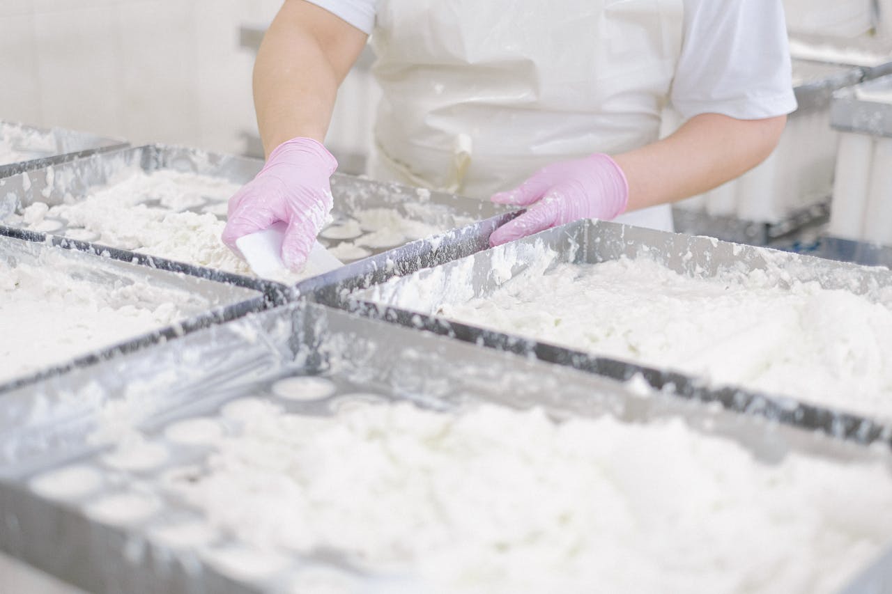 A person using pink gloves to prepare dough in a commercial baking facility.